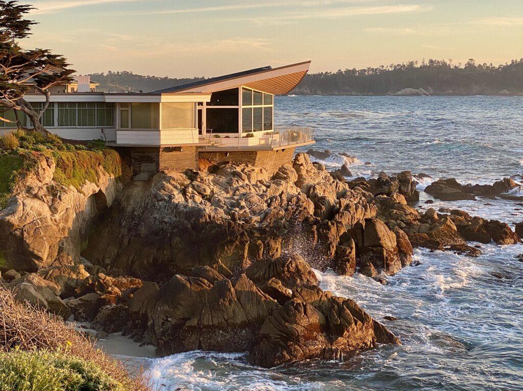 Butterfly House on Carmel Point with its wing-shaped roof over the rocky shoreline